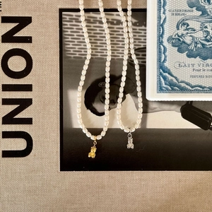 Close-up of pearl necklaces with gold and silver bear pendants on a vintage magazine