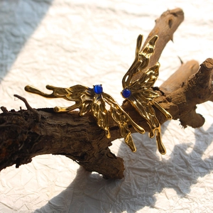 Golden butterfly wings earrings with blue natural stones on a wooden branch