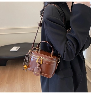 Detail view of a vintage brown leather box bag with gold zipper and branded tag charm