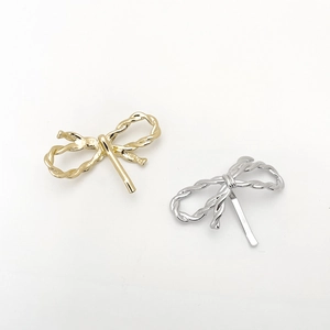 Detail of gold and silver metallic bow hair clips with twisted rope texture design