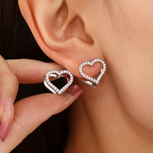 Silver heart-shaped stud earrings with sparkling white cubic zirconia on model's ear