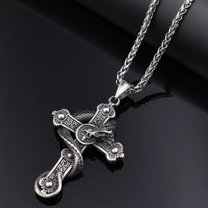 Macro detail of gothic dragon wrapped around a skull cross pendant in silver metal