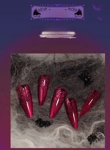 Detail of pink stiletto fake nails featuring black spider web prints for Halloween