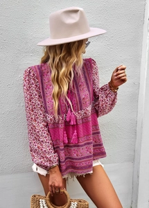 Detail of pink Bohemian printed blouse featuring tassel neckties and vibrant floral patterns