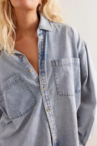 Detail view of light blue denim shirt showing collar and double front chest pockets