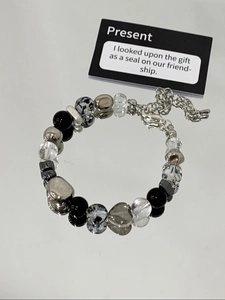 Detail of beaded heart bracelet with black and clear beads on mirror base
