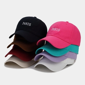 Multiple colors of cotton baseball caps with PARIS embroidery stacked in neat rows