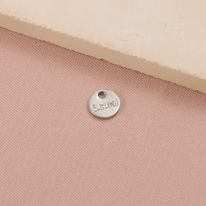 Detailed close-up of a silver stainless steel round pendant charm with S.Steel engraving