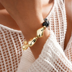 Gros plan de perles métalliques dorées irrégulières et de perles noires polies sur un bracelet
