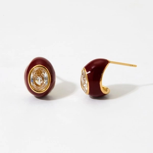 Macro shot of vintage gold stainless steel earrings with red enamel and zircon stones