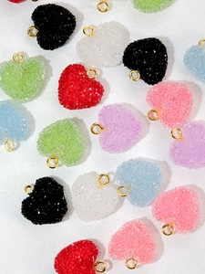 Close-up of heart-shaped sugar-coated candy resin charms with gold metal rings