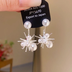 Close-up of silver flower stud earrings with radiant spikes and inlaid white pearls