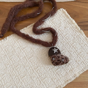 Détail du pendentif cœur en peluche avec imprimé léopard et étoiles sur corde tressée