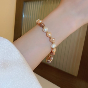 Detail view of French retro baroque multi-color pearl bracelet with gold bead accents on wrist