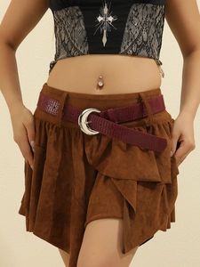 Detail of burgundy crocodile pattern belt with silver crescent buckle on brown skirt