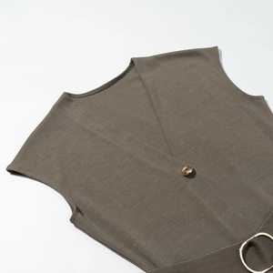 Detail of olive brown sleeveless midi dress featuring gold button and large circular belt buckle