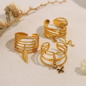 Detailed view of gold multi-layered open rings with feather, snake, and butterfly charms