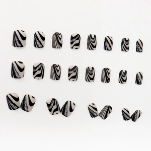 Black and white wave pattern press-on nails with silver glitter details on white background