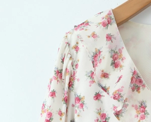 Detail of floral V-neck dress featuring ruffle trim and chiffon fabric on wood hanger