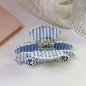 Detailed view of a striped acetate hair claw clip with blue flowers and rhinestones