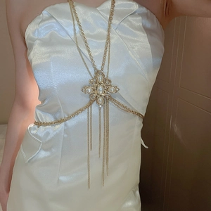 Close-up of a gold body chain with a cross pearl pendant and crystal fringe detail