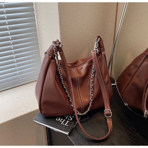 Detail of brown PU leather shoulder bag with silver chain and adjustable strap