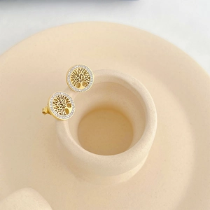 Detail of gold tree of life stud earrings with rhinestone inlay on beige base