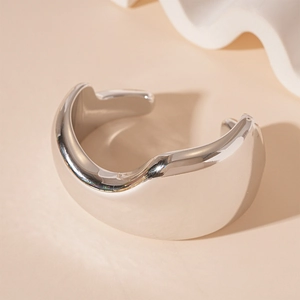 Detailed close-up of glossy silver irregular wavy cuff bracelet with mirror finish design