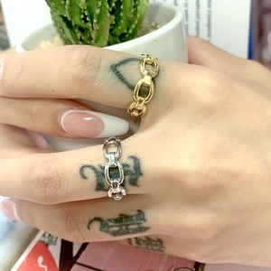 Close-up of gold and silver stainless steel Cuban chain rings on a female hand