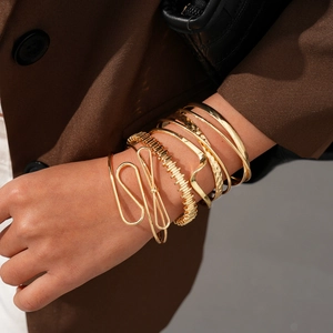 Gros plan de bracelets dorés empilables avec textures variées et un design de nœud torsadé