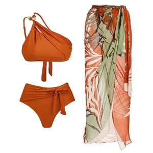 Detailed view of burnt orange ribbed one-shoulder bikini with tropical leaf beach sarong