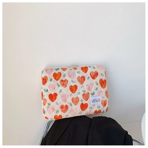 Detailed view of quilted fabric laptop sleeve with orange pink hearts and leaf patterns