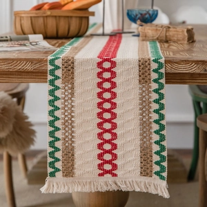 Bohemian striped table runner with red geometric patterns and fringe on wooden table