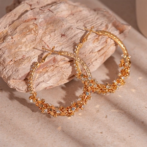 Golden geometric hoop earrings with sparkling diamonds set against a natural stone base