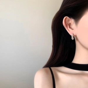 Exquisite silver-colored C-shaped twisted earrings with pavé zircons worn by a model