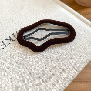 Detail of irregular wave flocking hair clip in dark brown velvet on beige linen