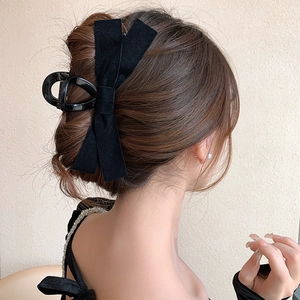 Detail of a large black velvet bow hair claw clip worn on a low bun hairstyle