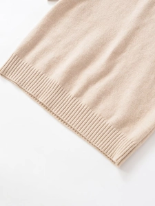 Detail shot of the beige knitted fabric showing the ribbed hem and texture