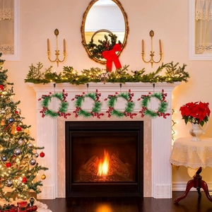 Detailed view of four small Christmas wreaths with red berries and pine needles by a fireplace