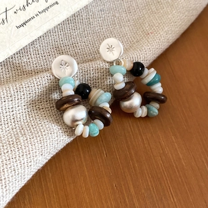 Close-up of bohemian earrings with silver star studs and colorful shell stone beads