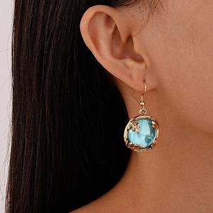 Close-up of vintage light blue resin earring with golden leaf frame on a model