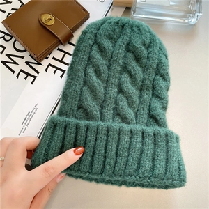 Close-up of dark green cable knit beanie with thick wool texture and stylish design