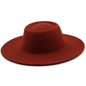 Top view of a red wool felt boater hat with a wide flat brim and oval crown structure