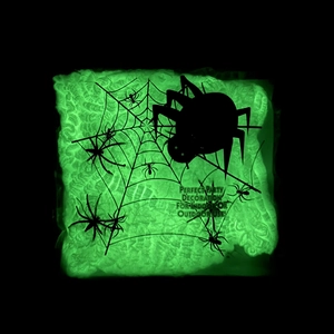 Close-up of glowing green Halloween spider web panel with black spiders for party decor
