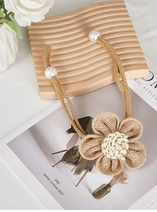 Detail of jute flower curtain tieback with wooden rope and white pearl fasteners