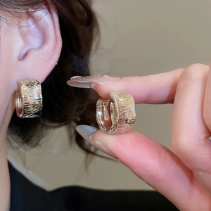 Macro shot of 18K gold plated textured hoop earrings with irregular folded metal ripple