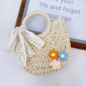 Detailaufnahme der Strohhandtasche mit Spitzenschleife und bunten 3D-gestrickten Blumen