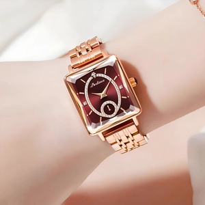 Close-up of rose gold square watch with a crimson diamond-set dial on a female wrist