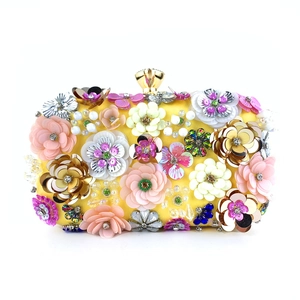 Detailed macro view of 3D sequin flowers and crystal beads on a yellow evening bag