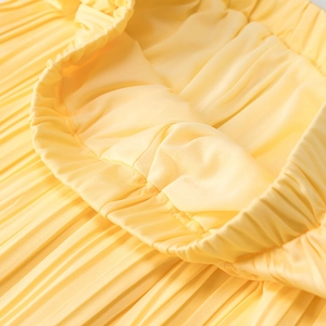 Détail de la taille élastique d'une jupe plissée jaune avec un tissu texturé léger